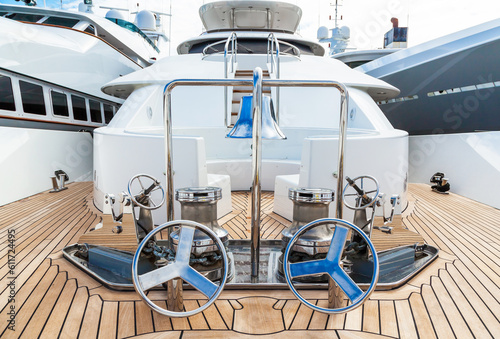 The bow of the yacht with teak deck, with anchor stops, part of the anchor chain, winch for tightening and ship bell made of stainless steel. © Сергей Жмурчак
