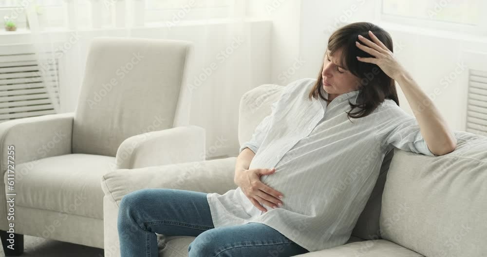 Exhausted pregnant woman seeks solace on the couch. With a weary expression and a gentle sigh, she takes a moment to catch her breath and find respite from the physical demands of pregnancy. Exhausted pregnant woman seeks solace on the couch. With a weary expression and a gentle sigh, she takes a moment to catch her breath and find respite from the physical demands of pregnancy.