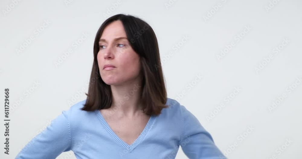 Caucasian woman stands on a white background, putting her hand to her forehead, looking for something, glancing around. In the end, she turns to the camera and shrugs her shoulders in uncertainty. Caucasian woman stands on a white background, putting her hand to her forehead, looking for something, glancing around. In the end, she turns to the camera and shrugs her shoulders in uncertainty.