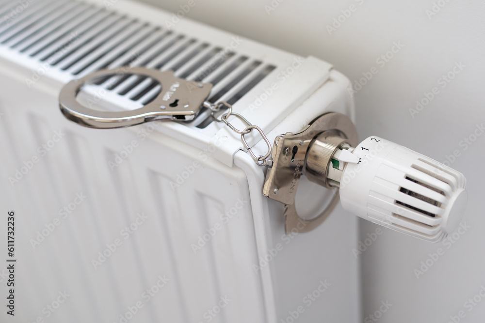 Handcuffs hanging on radiator near white wall indoors Handcuffs hanging on radiator near white wall indoors