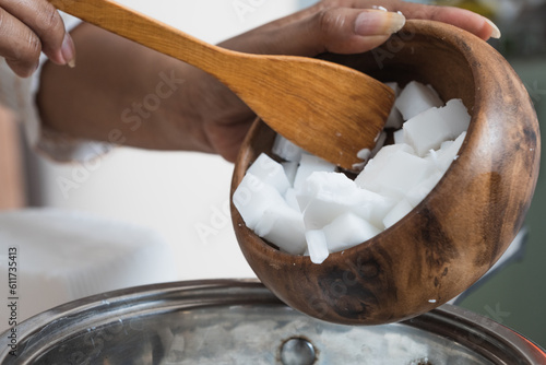 Female hands holding a wooden bowl with glycerin. Organic soap manufacturing process