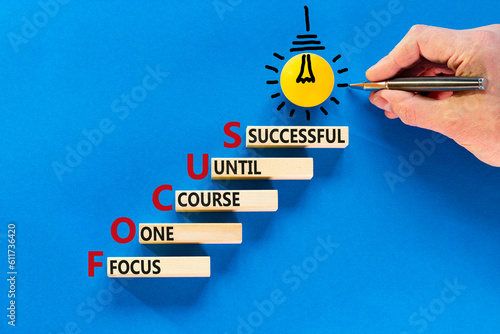 FOCUS follow one course until successful symbol. Concept words FOCUS follow one course until successful on wood block. Blue background. Business FOCUS follow one course until successful concept.