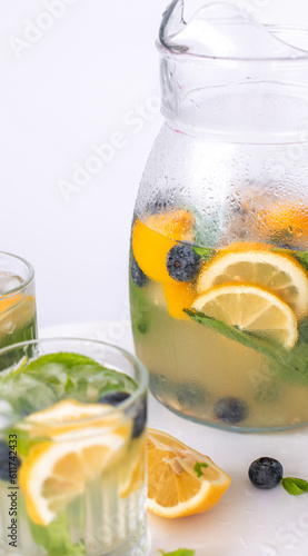 lemonade in a glass and a jug on a white background. Summer refreshing drink. Cold detox water with lemon