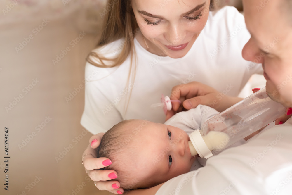 young parents hold the baby in their arms. family lifestyle photo with baby. family concept. parents bottle feed baby young parents hold the baby in their arms. family lifestyle photo with baby. family concept. parents bottle feed baby