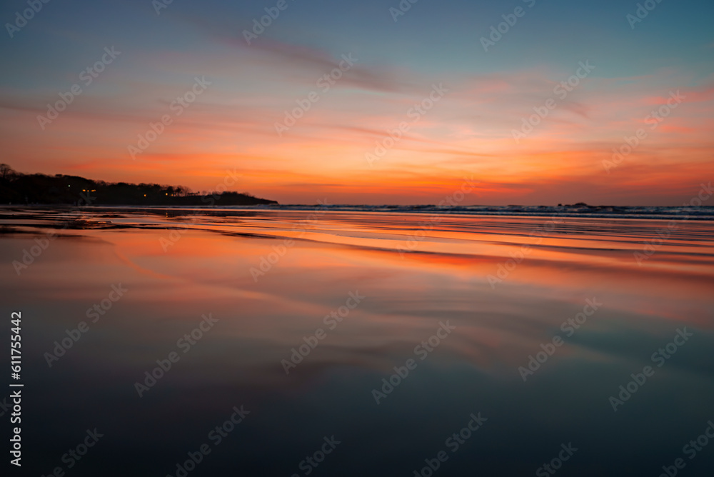 Tranquil view of beautiful waves in seascape and sandy beach with reflection of sunlight under cloudy sky during sunset at Costa Rica, nature and travel concept.