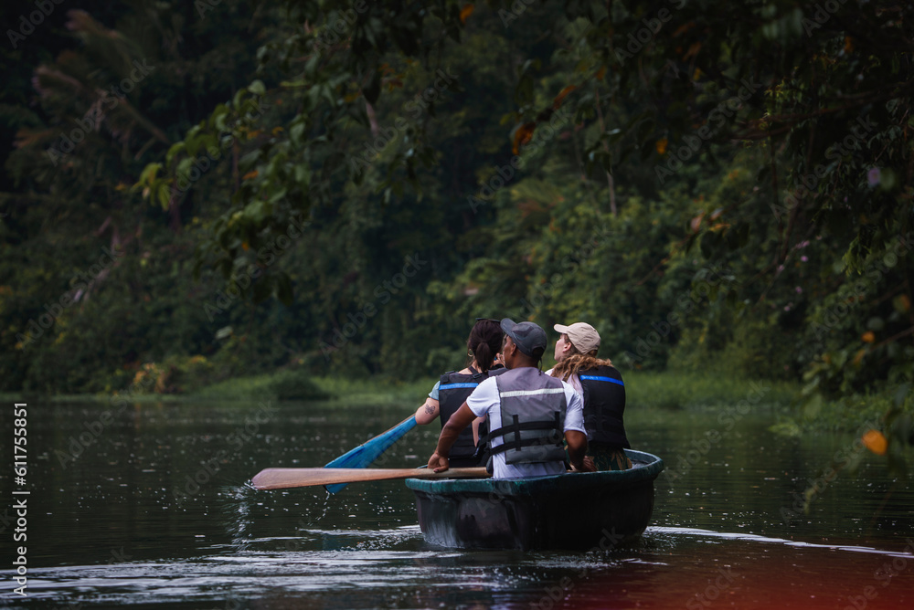 Male and female tourists enjoying rowboat tour exploring along the Tortuguero canal and forest in Costa Rica.