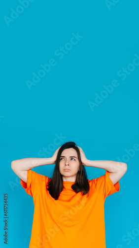 Unsatisfied Girl Touching Head, Frustration Concept - Empty Space, Disgruntled Expression, Isolated Blue Background. © Yauhen