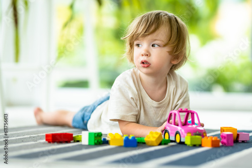 Cute toddler boy playing with blocks construction toy set on the floor at home. Daytime care creative activity. Kids having fun with toys. Educational learning games.