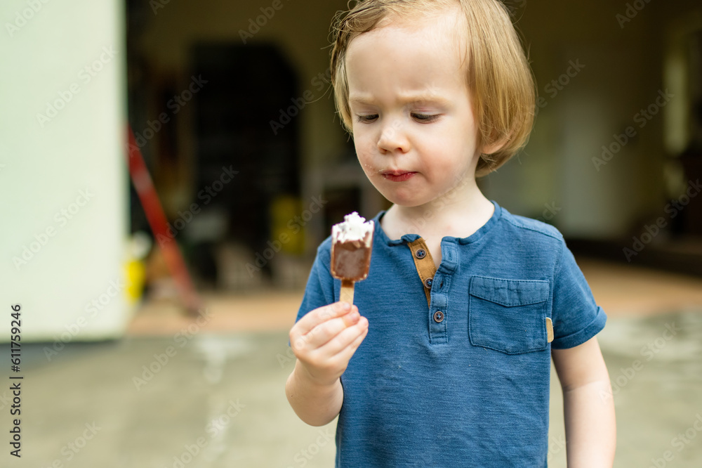 Cute toddler boy eating tasty fresh ice cream outdoors on warm sunny summer day. Children eating sweets. Cute toddler boy eating tasty fresh ice cream outdoors on warm sunny summer day. Children eating sweets.
