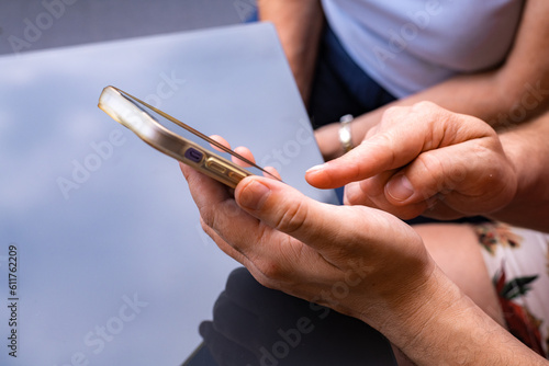Grown man's hand pointing finger at close-up screen of cell phone while showing something to nearby person. 
