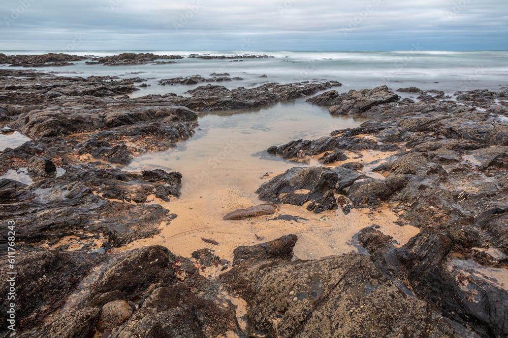 Long exposure image of rocky beach with tidal pool at Vila Nova de Milfontes, Portugal