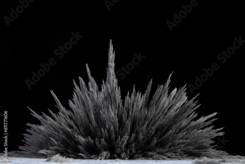Reaction of iron dust to a magnetic field. Iron filings spikes. Neodymium magnet. Isolated on a black background. Visualisation of magnetic field.