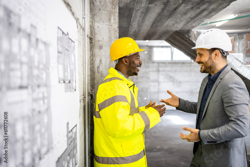 Construction worker and structural engineer discussing about new building project.