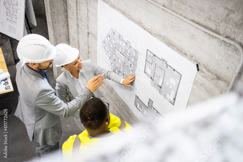 Fényképezés Team of structural engineers working together on construction site and discussing project plan or blueprint