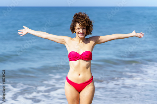 Happy woman in pink bikini standing near sea © javiindy