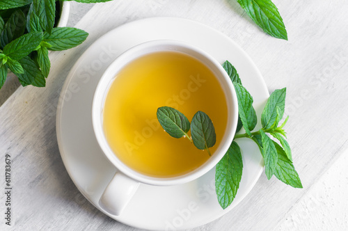 Cup of mint tea with fresh green mint leaves on rustic table, healthy herbal hot drink
