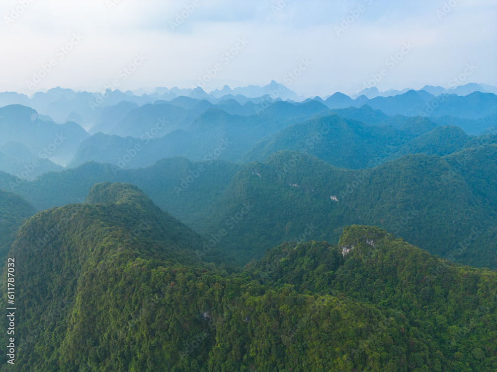 Aerial top view of forest trees and green mountain hills with fog, mist and clouds. Nature landscape background, Vietnam.