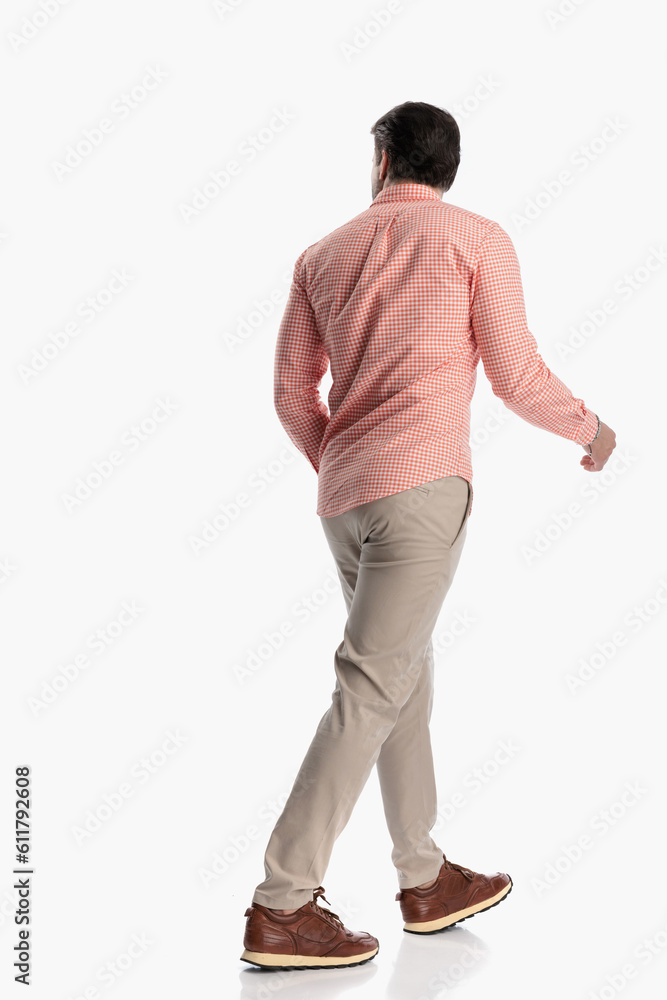rear view of young man in plaid shirt looking to side and walking rear view of young man in plaid shirt looking to side and walking
