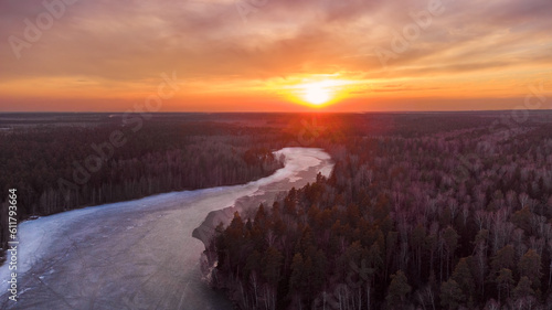 Winter sunset above winter forest with small rive