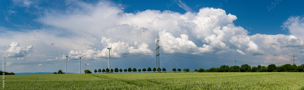 Panoramaaufnahme eines über das Land ziehenden Gewitters mit Wolkenfetzen am Himmel und landwirtschaftlich genutzten Äckern am Boden