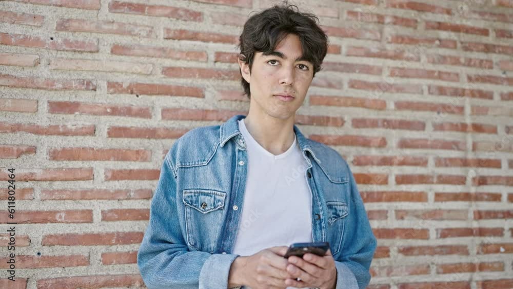 Young hispanic man using smartphone smiling over isolated brick background Young hispanic man using smartphone smiling over isolated brick background