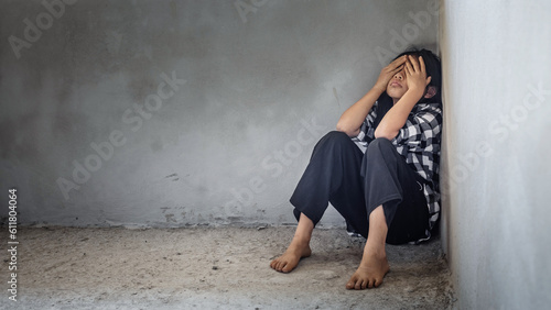 Sad despair young child girl sitting alone on floor concrete wall background