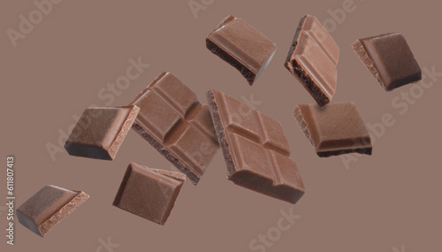 Pieces of chocolate bar falling on brown background