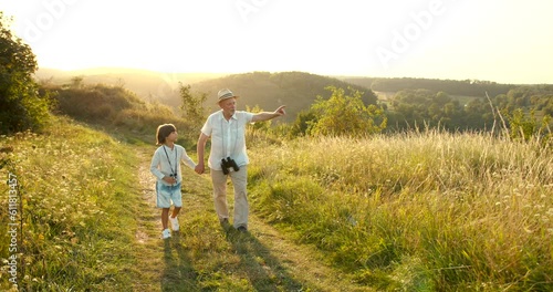 Grandfather and grandson walking at sunset in the field