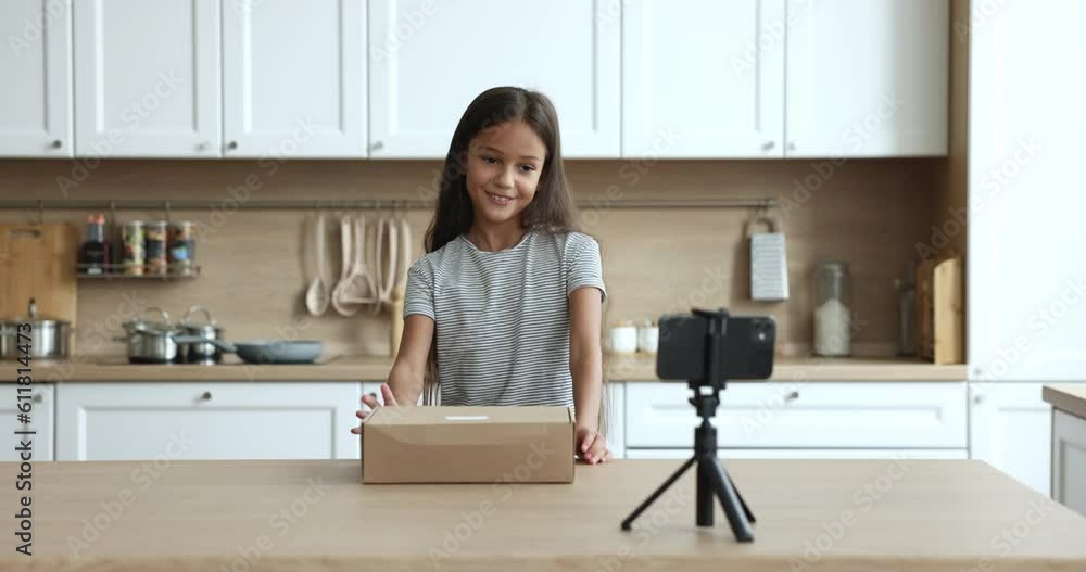 Cute little girl record on smartphone camera unpacking of bought goods ...