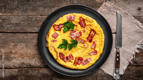 Fried stuffed omelet. Tasty omelet with fried bacon and fresh parsley on a plate, fork, knife on old wooden background with copy space for text. Delicious egg breakfast. Vintage style. - generative ai