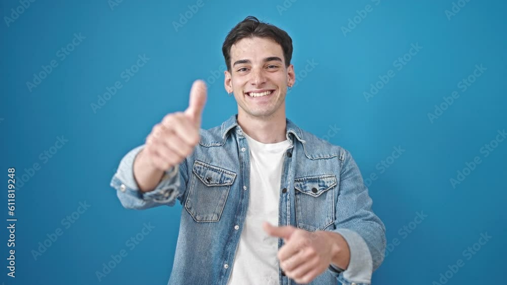 Young hispanic man smiling with thumbs up over isolated blue background Young hispanic man smiling with thumbs up over isolated blue background