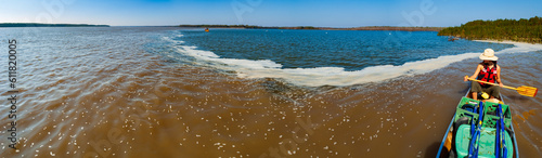 A female paddler looks on as the clearer, warmer waters of the Arkansas River (blue) flow into the colder, turbid Mississippi River (brown) near Arkansas City, Arkansas (panorama) photo