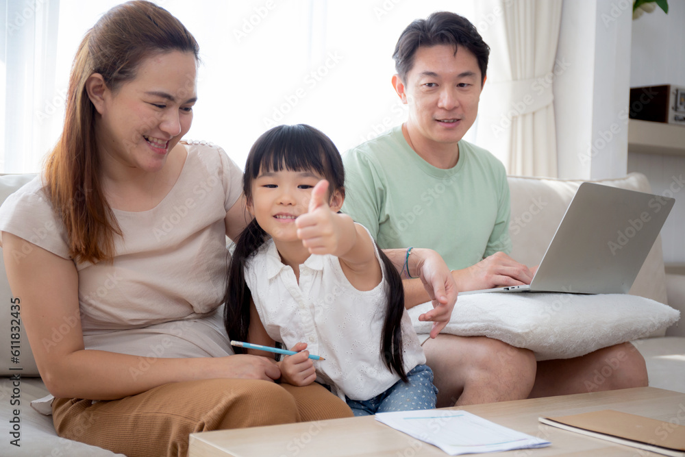 Happy family with mother teaching homework with daughter and father working with laptop on sofa in living room at home, mom explaining schoolwork with kid together, lifestyles and education. Happy family with mother teaching homework with daughter and father working with laptop on sofa in living room at home, mom explaining schoolwork with kid together, lifestyles and education.