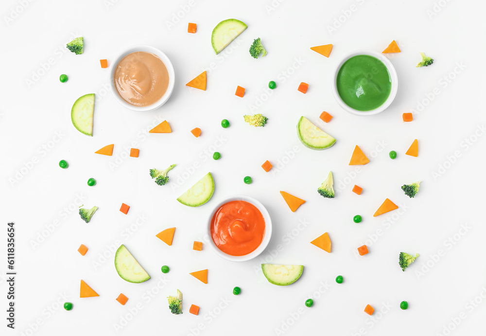 Composition with bowls of healthy baby food and fresh vegetables on white background Composition with bowls of healthy baby food and fresh vegetables on white background