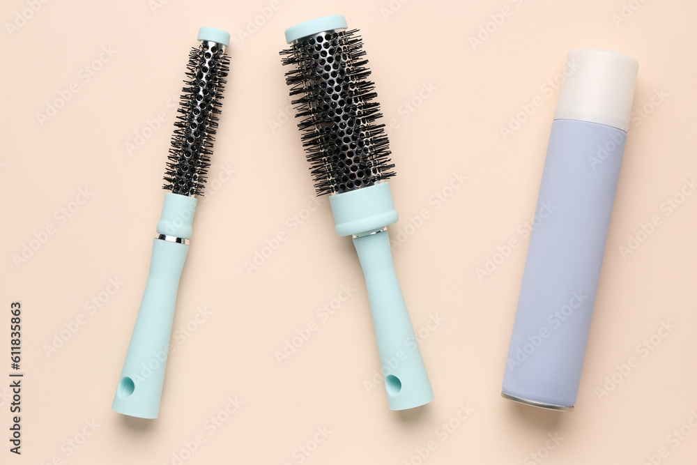 Round brushes with hair spray on beige background Round brushes with hair spray on beige background