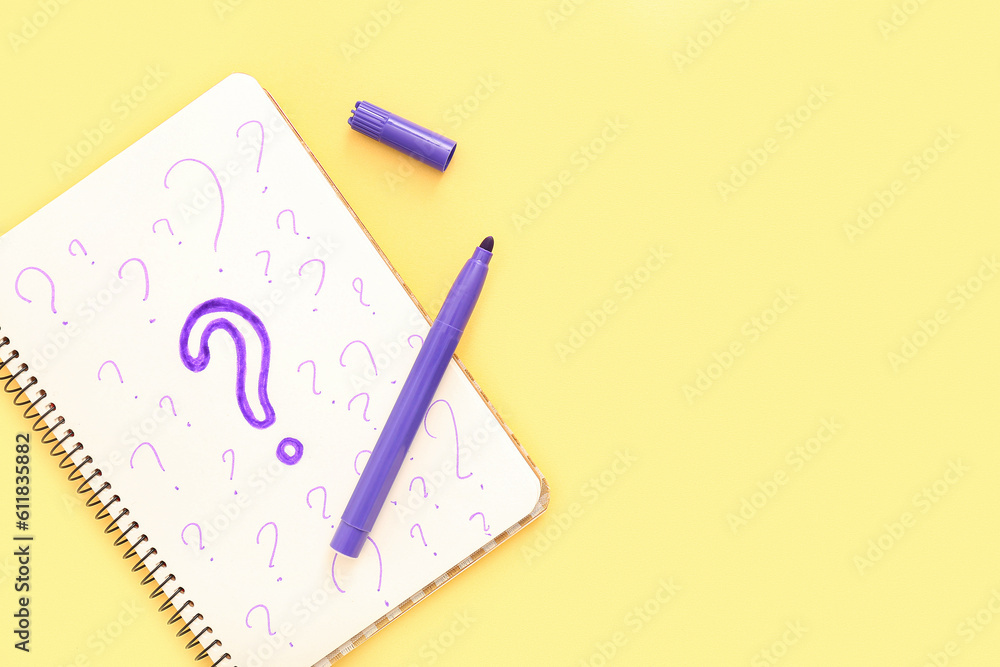 Notebook with drawn question marks and marker on yellow background Notebook with drawn question marks and marker on yellow background