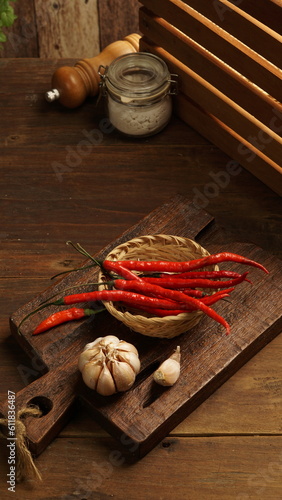 snacks in a small round bowl and garlic and red chili in the photo with a wooden dark brown background photo