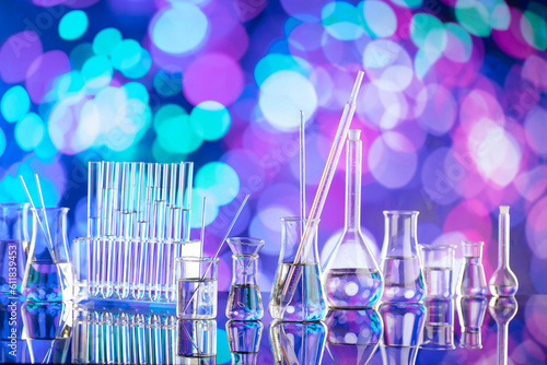 Laboratory investigations. Glass tubes and beakers on blue bokeh background.