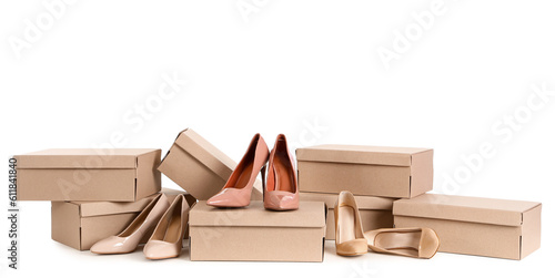 Cardboard boxes with beige high-heeled shoes on white background
