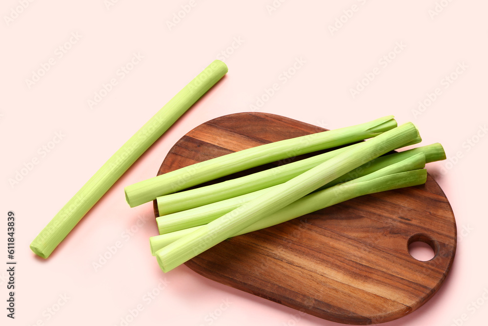 Board with fresh leeks on pink background Board with fresh leeks on pink background