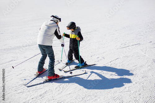 Little boy learning how to ski with his coach photo