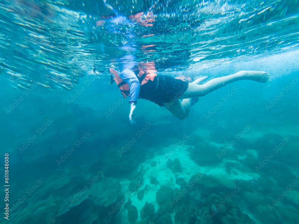 Young woman snorkeling scuba diving with life jacket at the Great Barrier Reef in the tropical	
