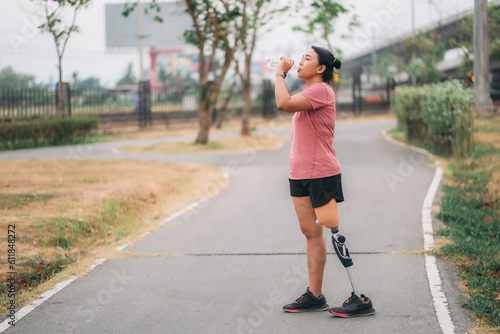 Woman wearing prosthetic equipment sit down after exercising in a park. Female walking and exercise works out outside.