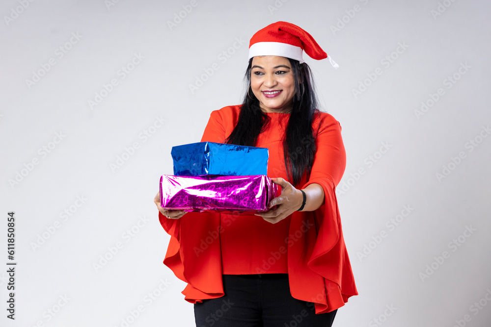 Indian woman wearing Santa hat, holding gift box and celebrating Christmas. Indian woman wearing Santa hat, holding gift box and celebrating Christmas.