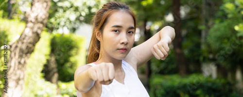 Young asian woman practicing kungfu qigong, martial arts, self defense technique in green urban park photo