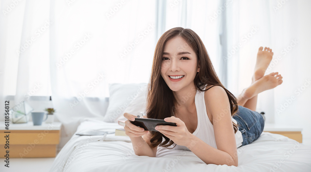 Asian woman with attractive smile use tablet smartphone on white bed, Portrait young beauty sexy girl relax in bedroom. Technology people connection digital online marketing e-commerce concept banner Asian woman with attractive smile use tablet smartphone on white bed, Portrait young beauty sexy girl relax in bedroom. Technology people connection digital online marketing e-commerce concept banner