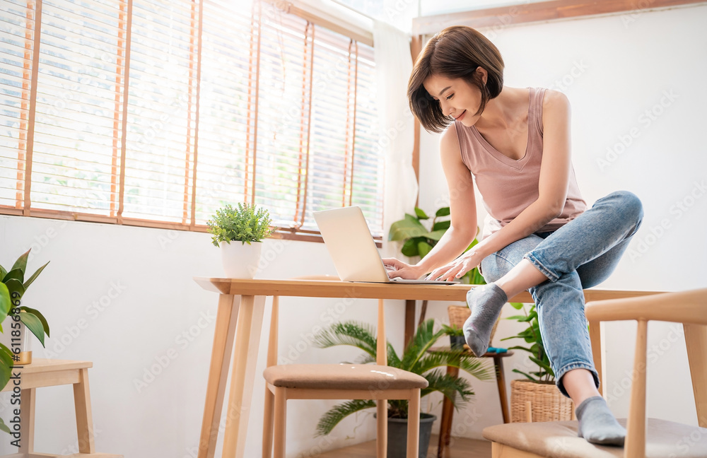 Portrait young beautiful asian creative woman relax sit on desk use computer laptop. Smile happy asian girl drink coffee at table home. Freelance small business asian owner sme work from home concept Portrait young beautiful asian creative woman relax sit on desk use computer laptop. Smile happy asian girl drink coffee at table home. Freelance small business asian owner sme work from home concept