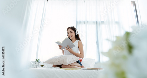 Free Download Portrait of young beautiful asian woman relax holding book listen to music from headphone in bedroom. Smile happy asian girl relaxing knowledge education university lifestyle, back to school concept - GFXLoad