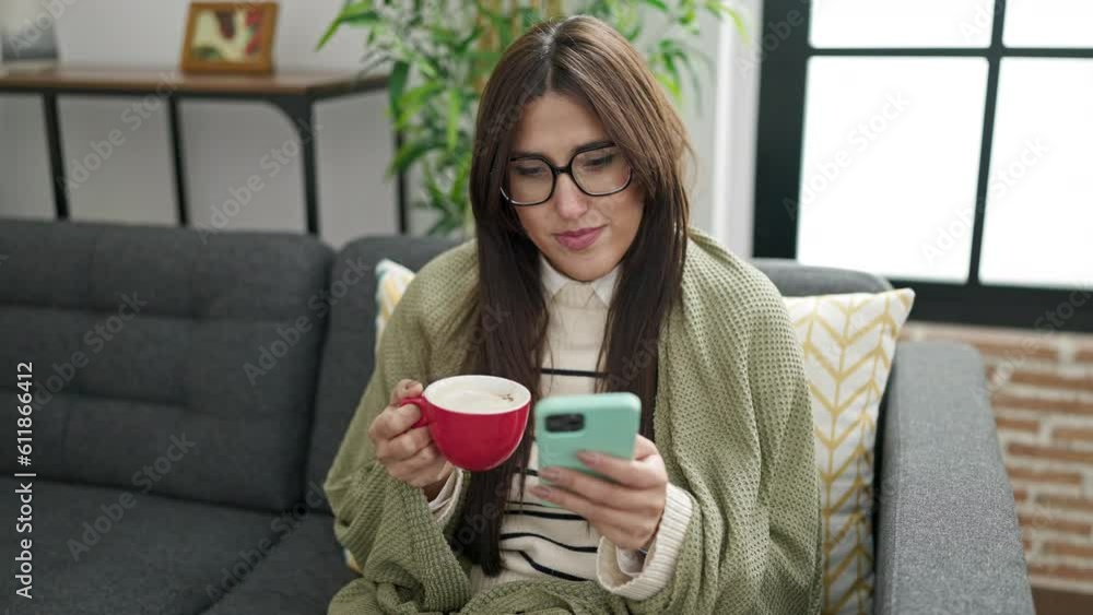 Young beautiful hispanic woman using smartphone drinking coffee at home