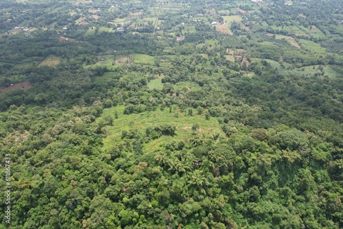 A mesmerizing drone photo of mountain ranges displaying vast green plateaus and lush trees.